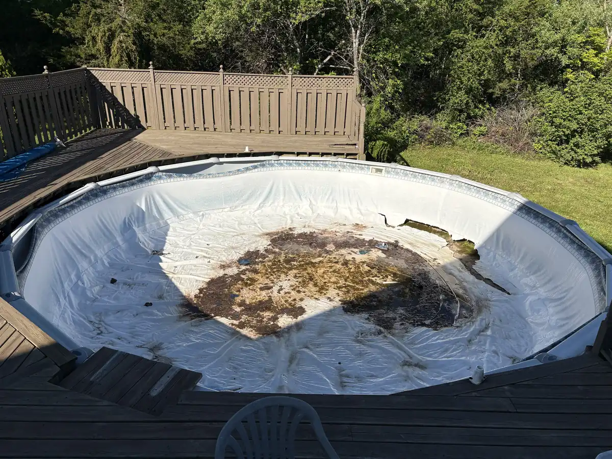 Round above ground pool with a torn, stained old liner