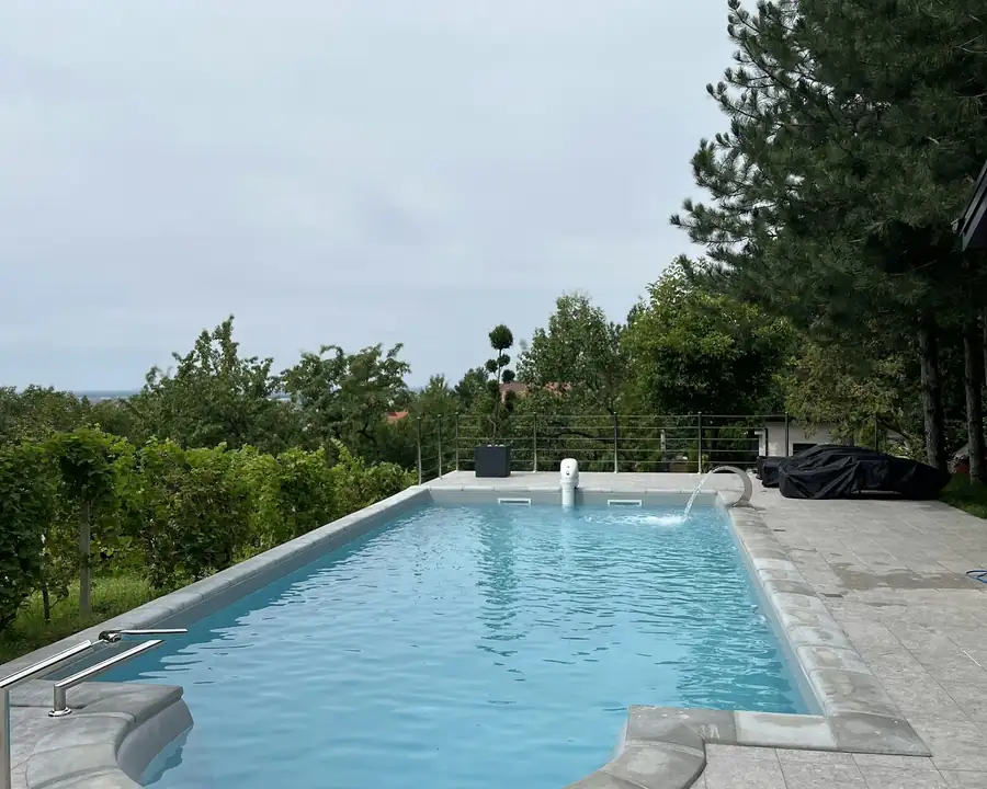 Backyard pool beside evergreens, heated to stretch the swim season into fall
