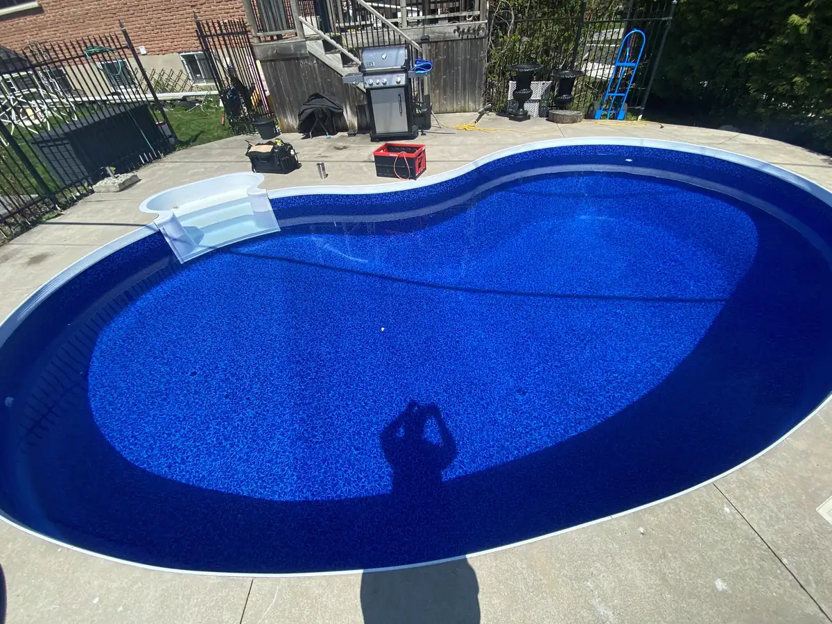 Kidney pool with a new deep blue vinyl liner installed by Limitless Pools