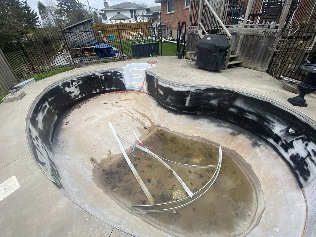 Kidney pool drained with the old liner cut out and black wall foam showing