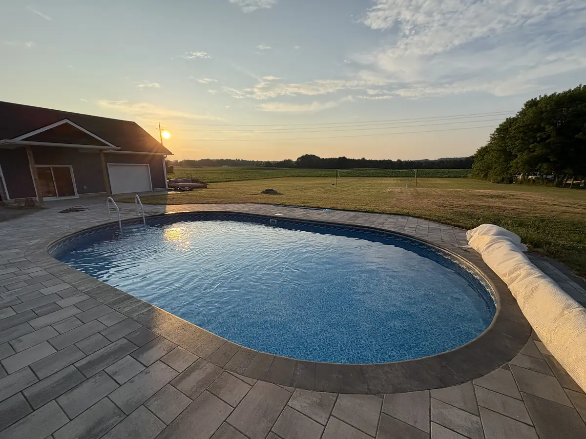 Oval pool on a rural lot, clear and blue at sunset after an opening