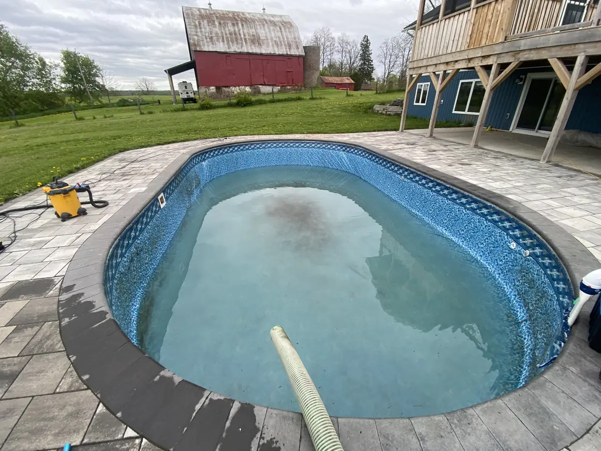 Oval pool partly refilled with cloudy, pale water