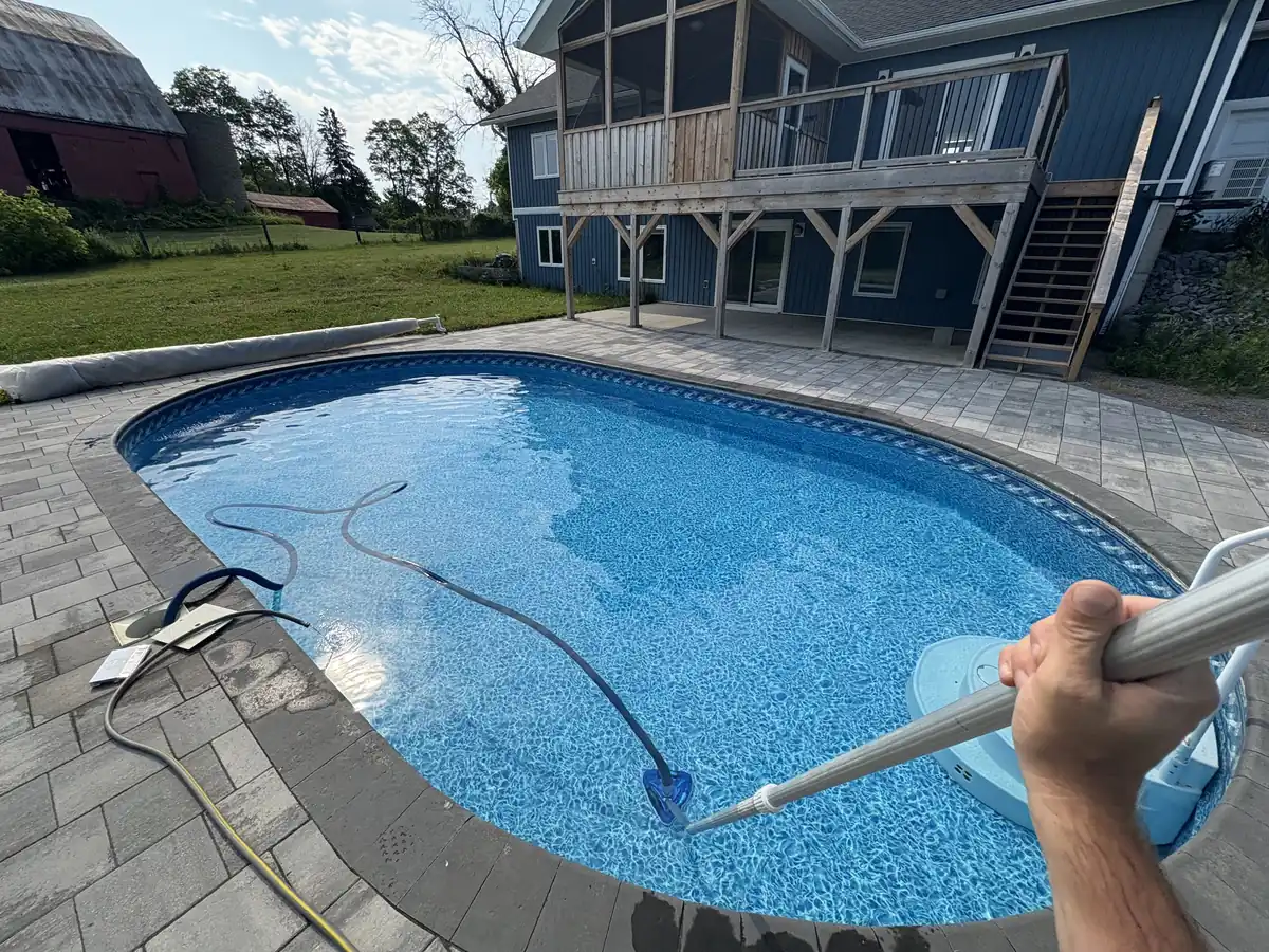Limitless Pools technician vacuuming a clear oval pool