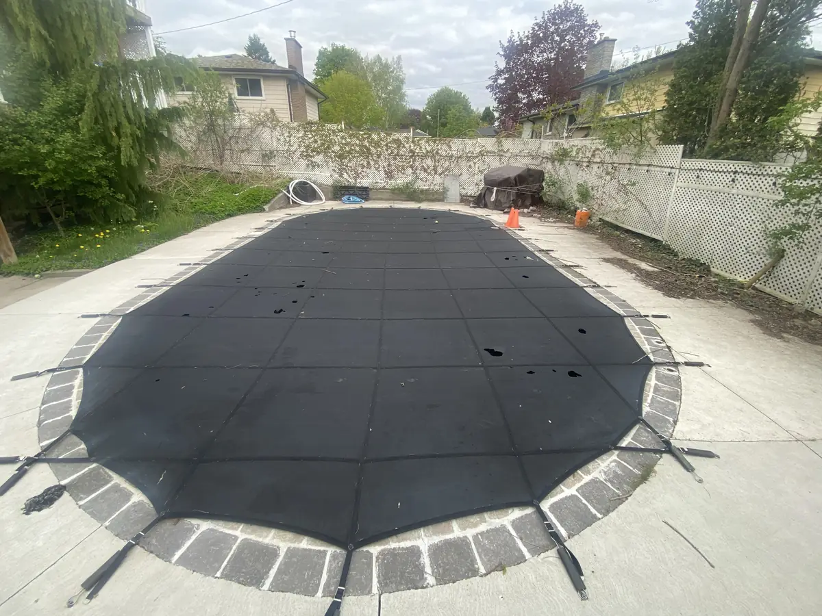 Black mesh safety cover installed on a freeform inground pool
